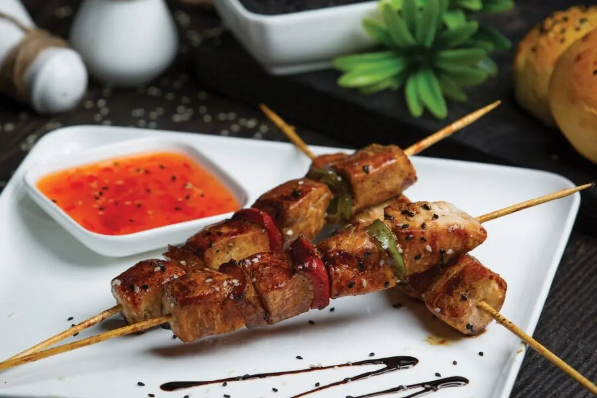 tiga tusuk sate di atas piring saji dan sambal